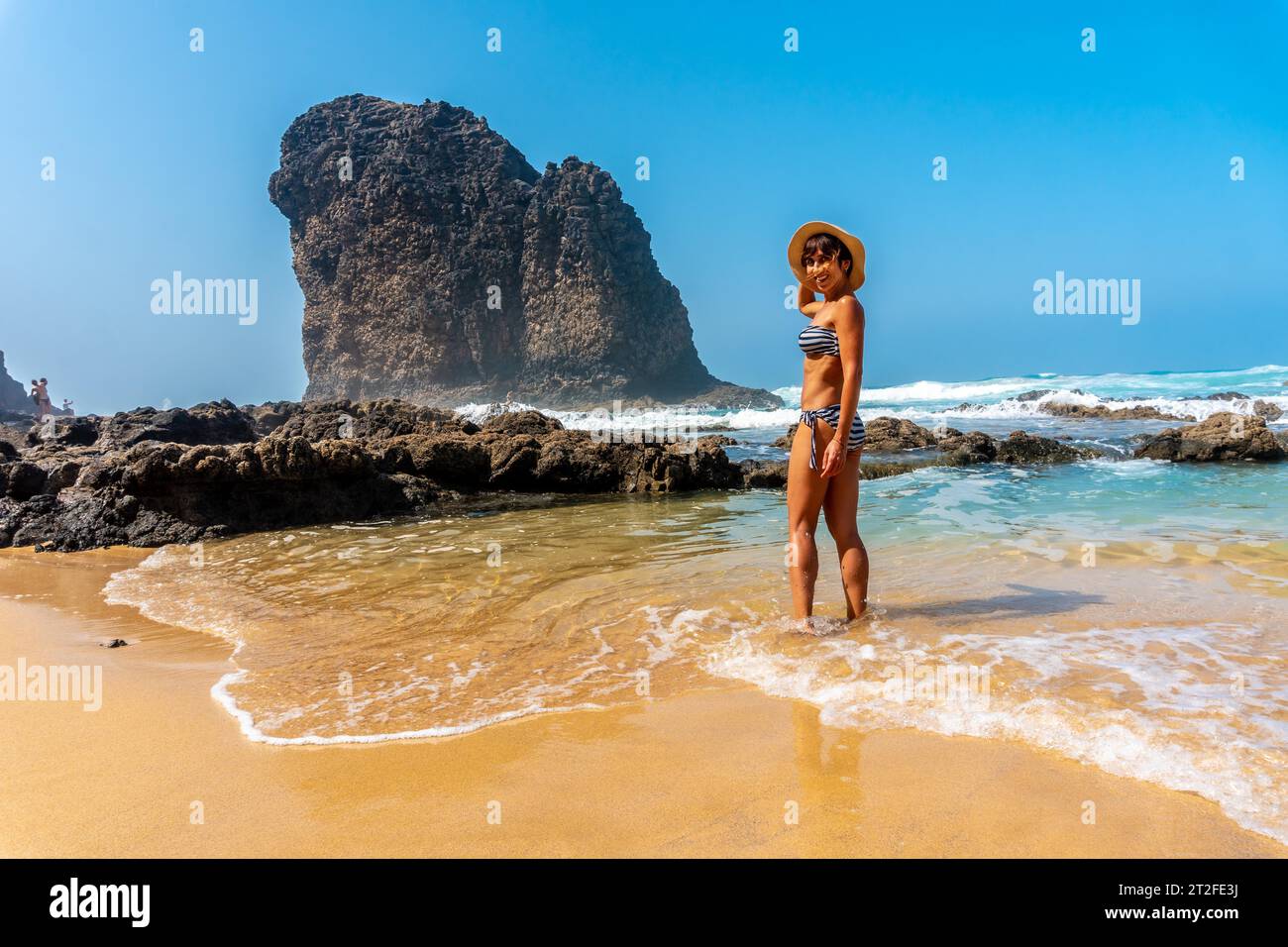 Un giovane turista sorridente nella Roque del Moro della spiaggia di Cofete del parco naturale di Jandia, Barlovento, a sud di Fuerteventura, Isole Canarie. Foto Stock