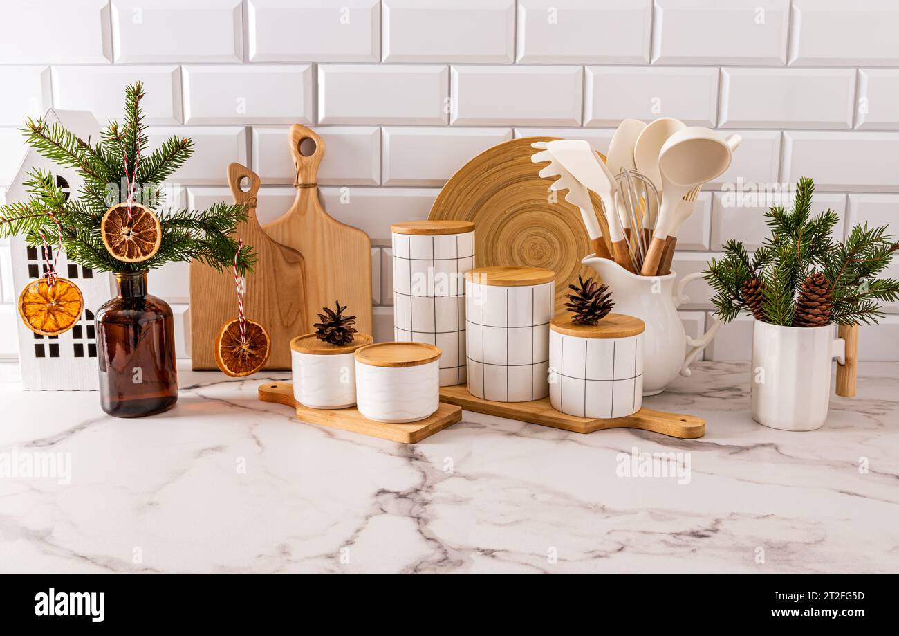 Splendido sfondo della cucina di Capodanno con un set di utensili da cucina e vasetti per conservare il cibo, decorati con rami natalizi con decorazioni naturali Foto Stock