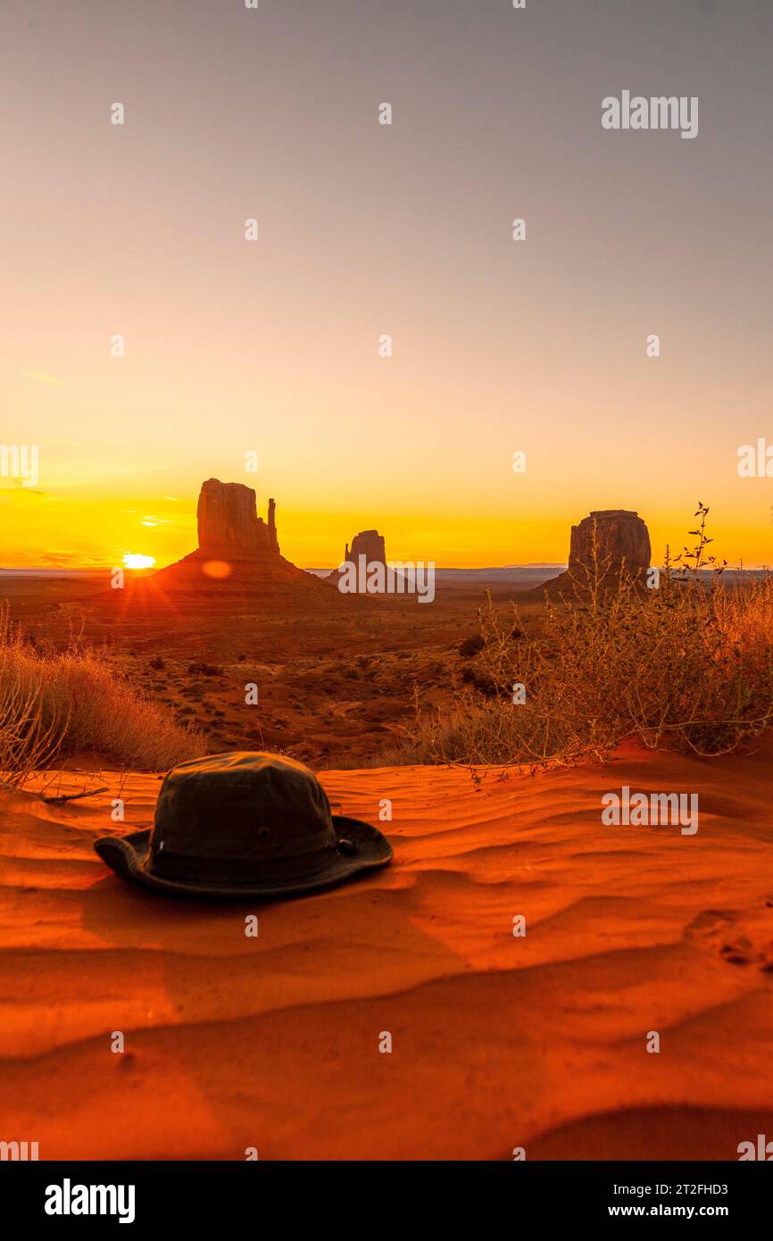 Un cappello verde sulla sabbia rossa all'alba nella Monument Valley, Utah. Foto verticale Foto Stock