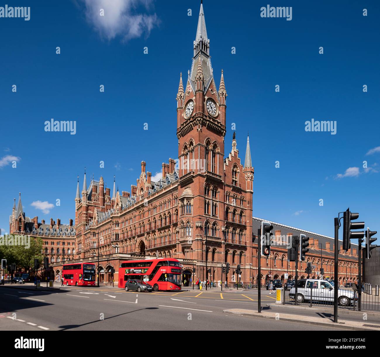 Stazione internazionale di St Pancras a Londra con autobus rossi che passano accanto alla sua iconica facciata gotica vittoriana sotto i cieli blu. Foto Stock