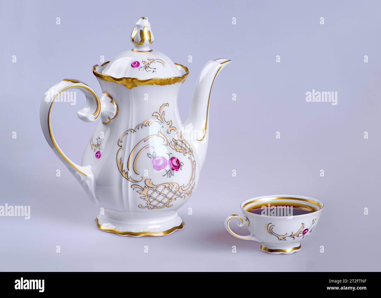 Un bollitore in ceramica e una tazza piena di caffè (tè) su sfondo grigio. Foto Stock