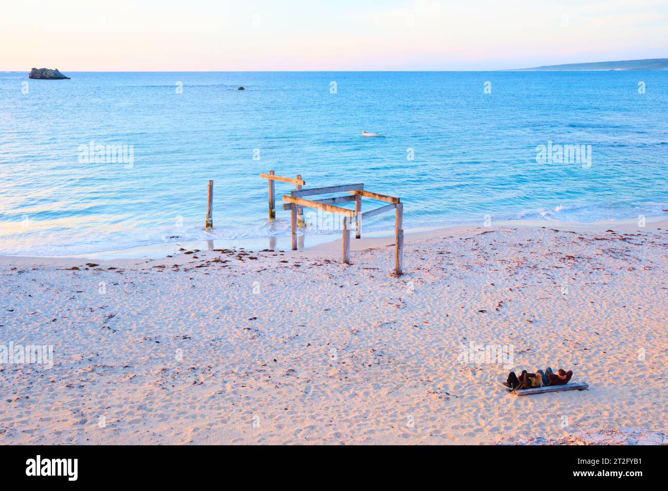 Resti del vecchio molo e due persone che guardano il tramonto a Hamelin Bay, nella regione sud-occidentale dell'Australia Occidentale. Foto Stock