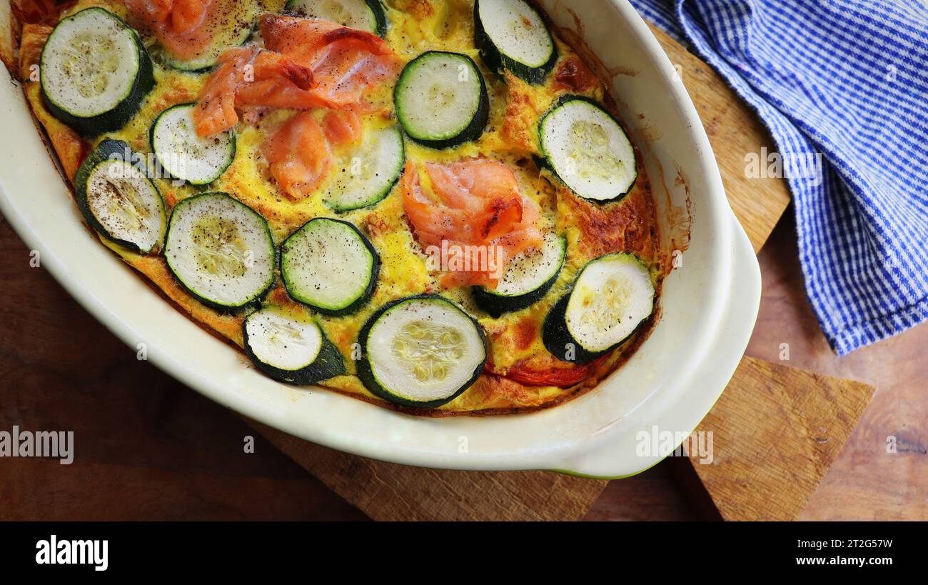 Gratin di zucchine con salmone e parmigiano su fondo ligneo. Torta estiva con zucchine . Foto Stock