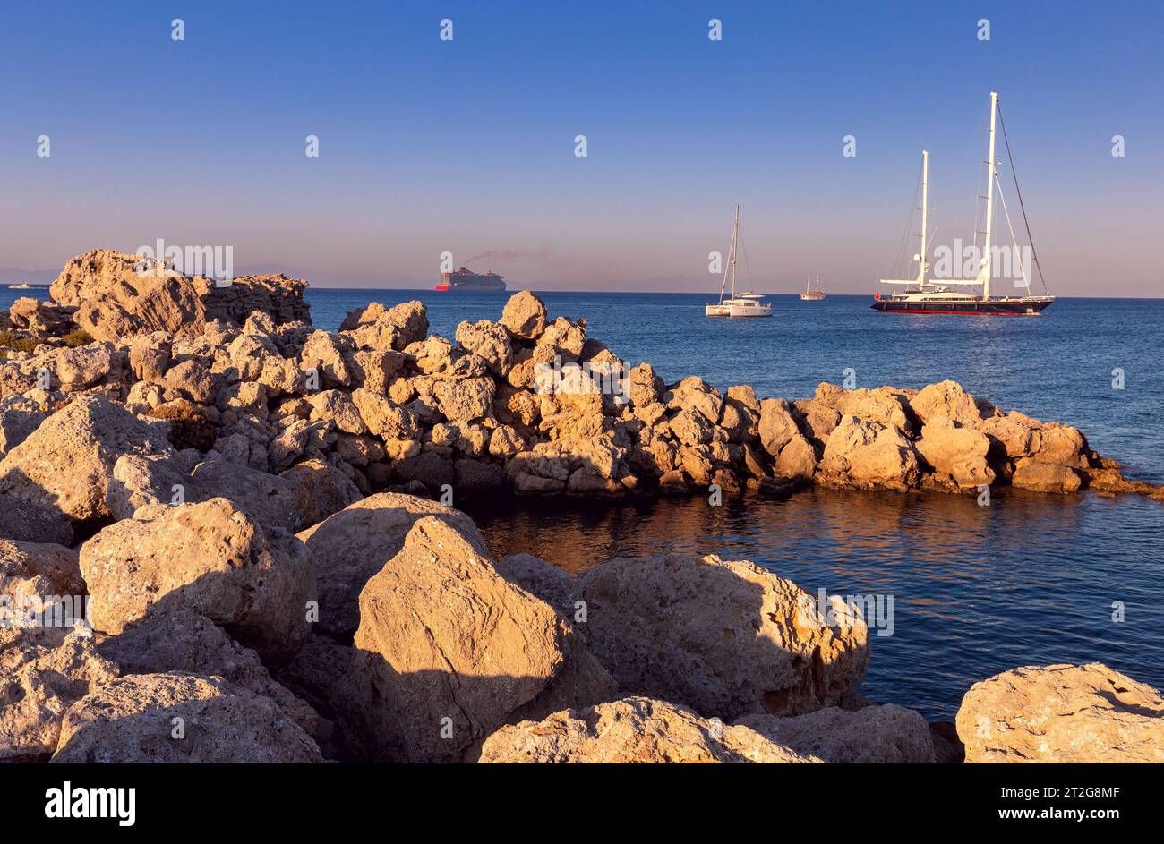 Vista delle rocce degli yacht e delle navi sulla costa dell'isola di Rodi al tramonto. Grecia. Foto Stock