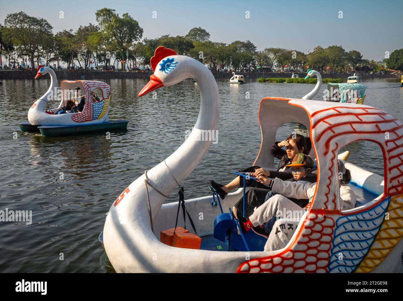 Tre bambini su un pedalò a forma di cigno sul lago Truc Bach, Hanoi, Vietnam Foto Stock