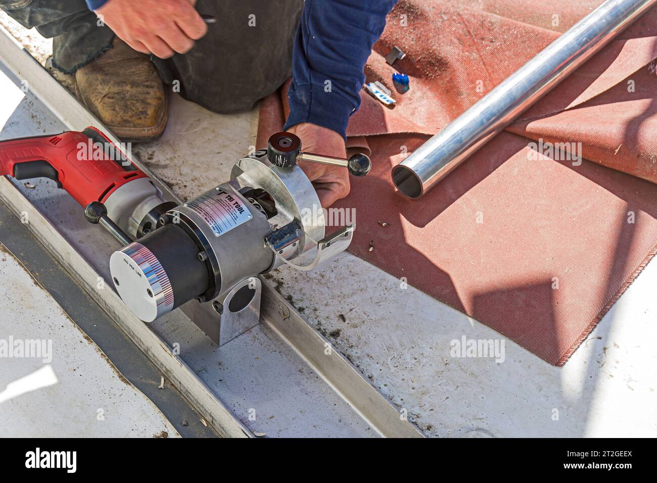 Un utensile per il rivestimento e la quadratura del tubo viene utilizzato su tubi in acciaio inox utilizzati sul tetto in un impianto di refrigerazione industriale a CO2. Foto Stock