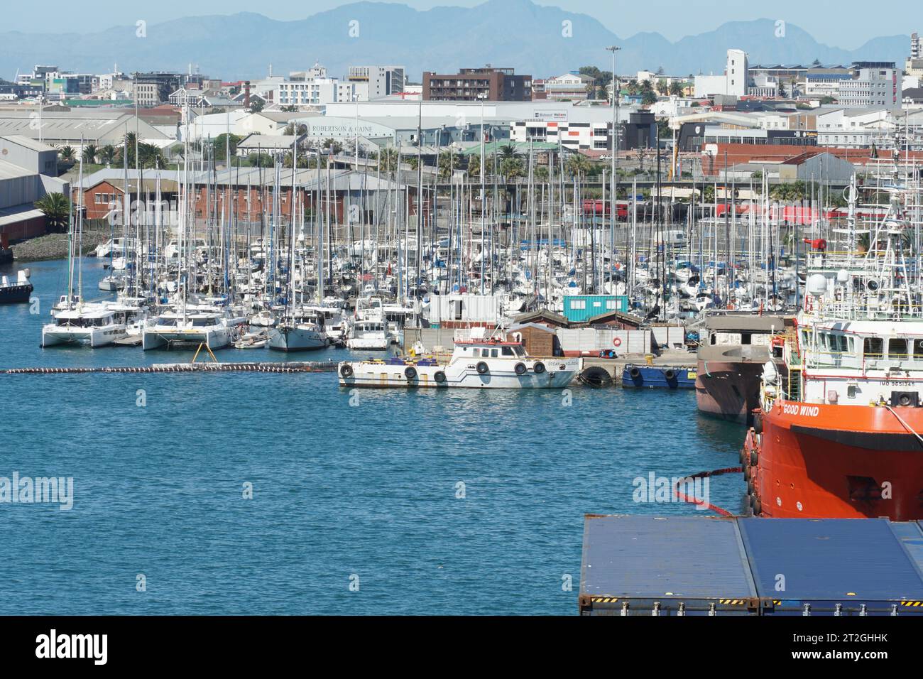 Yacht privati e barche a motore ormeggiati nel porto di città del Capo osservati da navi portacontainer accanto a ormeggio di riparazione. Foto Stock