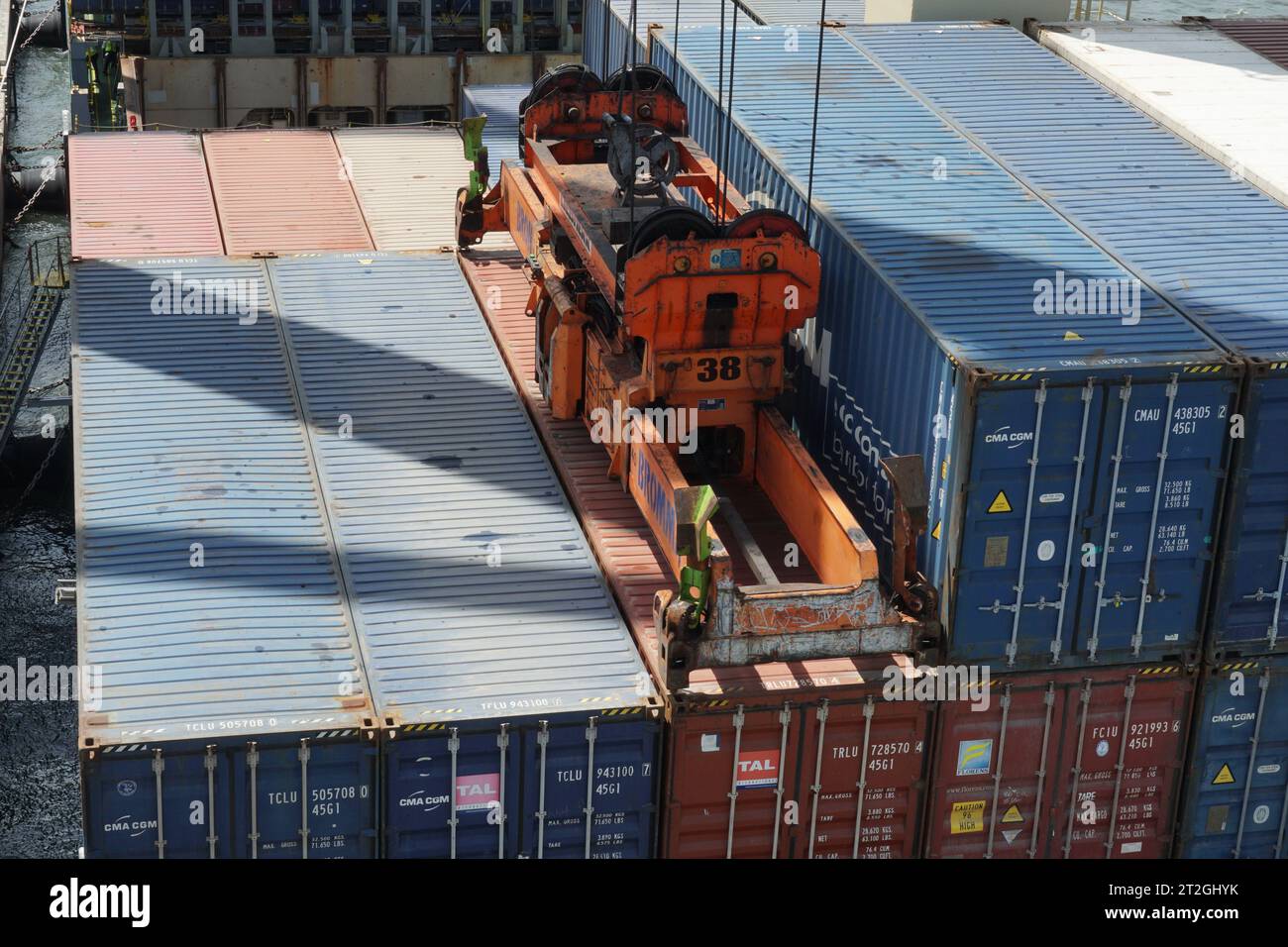 I container collegati all'unità di sollevamento delle gru a cavalletto azionate da stazionari vengono caricati sulla nave. Foto Stock