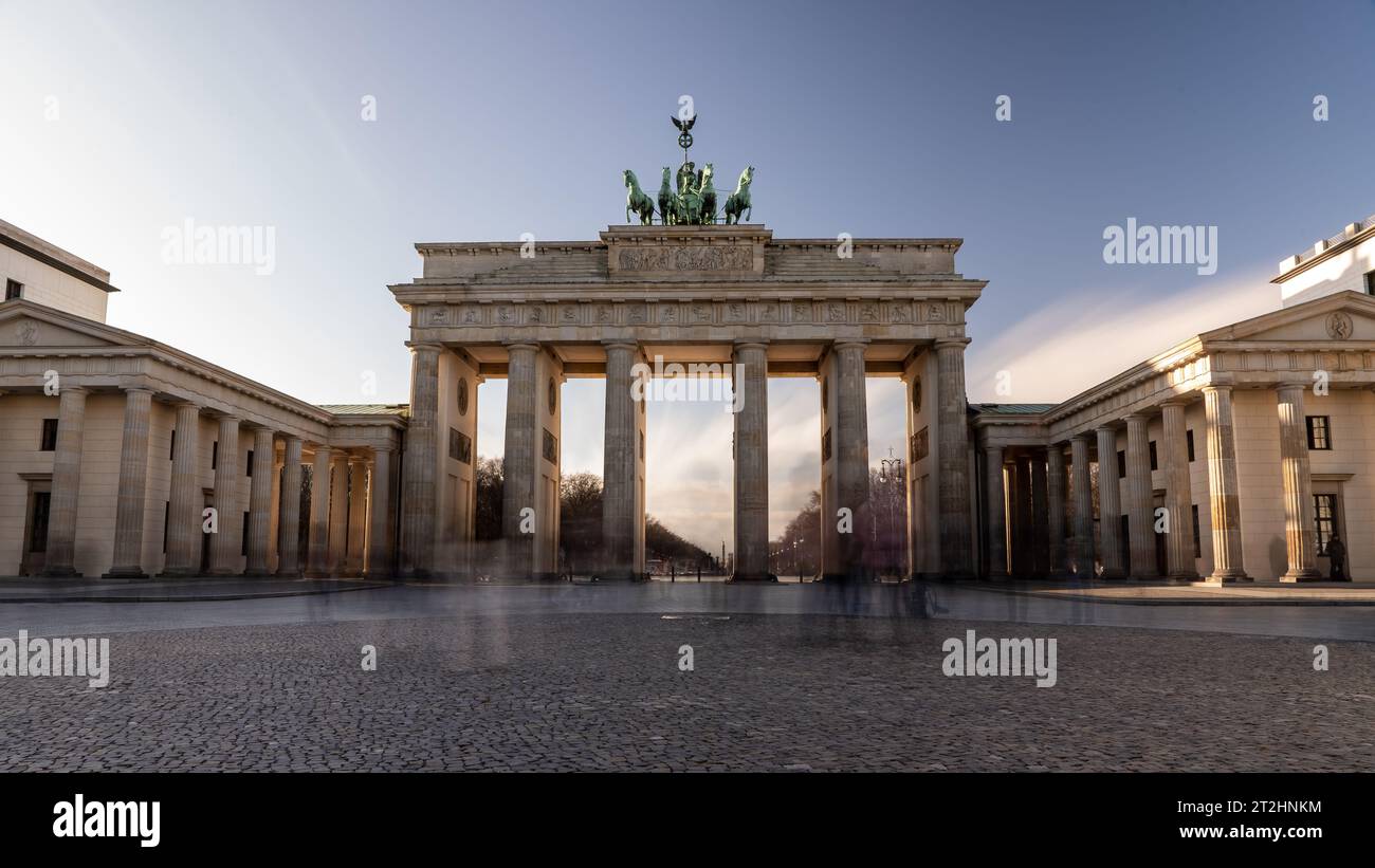 Lunga esposizione della porta di Brandeburgo a Berlino, in Germania, in una giornata di sole con veli di persone che passano Foto Stock