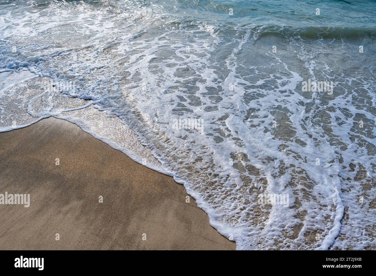 Onde, schiuma e sabbia della costa nel Mar Mediterraneo, Cesarea, Israele. Foto Stock
