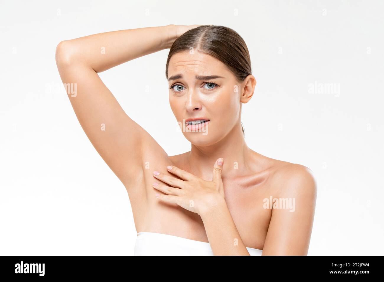 Donna caucasica imbarazzata in asciugamano con volto sconcertato che mostra ascelle su sfondo bianco isolato in studio di luce Foto Stock