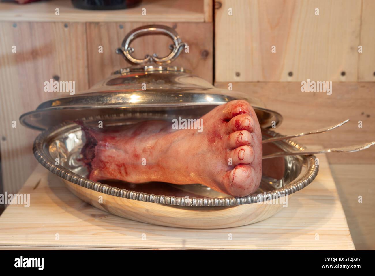 L'Aia, Paesi Bassi - 23 ottobre 2023: Effetti speciali di Halloween orrore nella vetrina del negozio, piede sanguinoso tagliato sul piatto d'argento Foto Stock