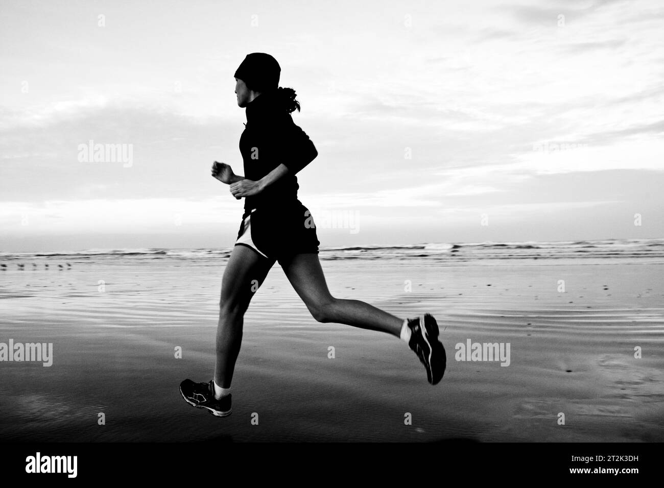 Immagine in bianco e nero di una donna che corre su una spiaggia. Foto Stock Immagine in bianco e nero di una donna che corre su una spiaggia. Foto Stock