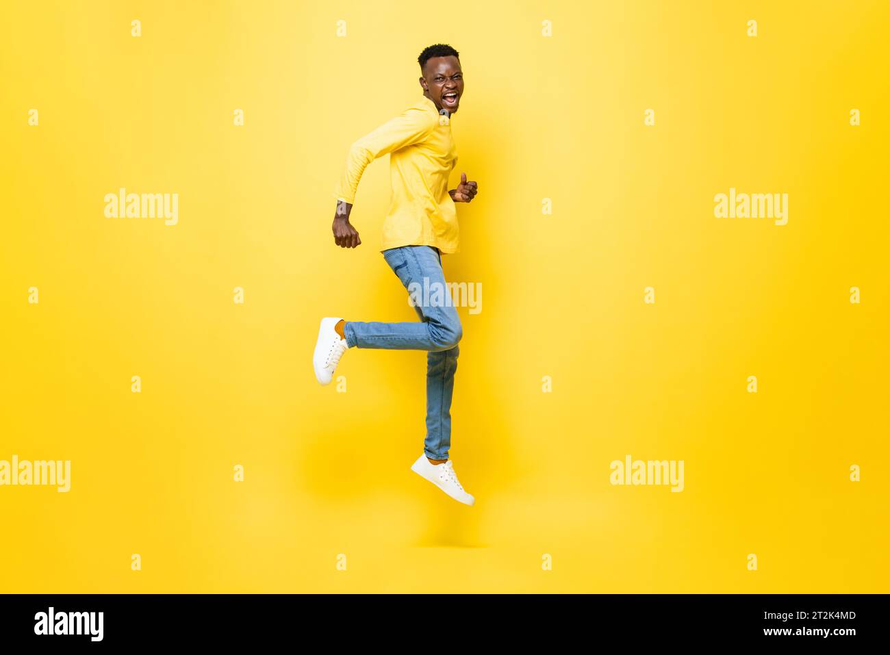 Ritratto a tutta lunghezza di un uomo africano estatico che salta su uno sfondo isolato di colore giallo da studio Foto Stock