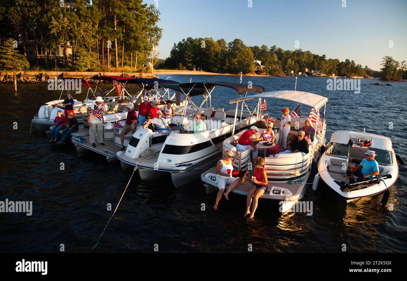 Una comunità di persone che vivono tutti su un lago legano le loro barche per una festa in una serata di sole. Foto Stock