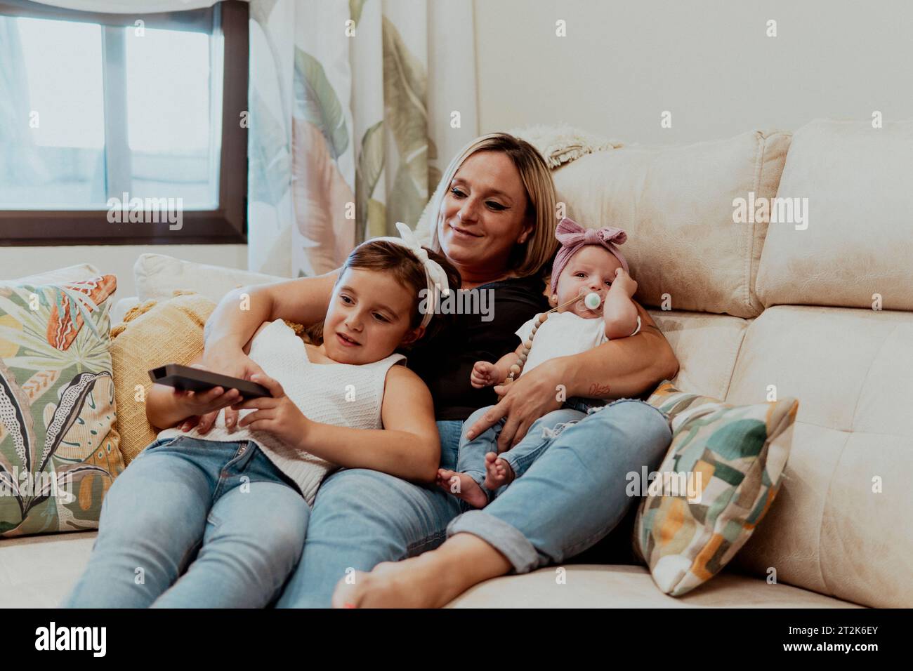 Mamma e figlia seduti sul divano che tiene il bambino in vita camera a casa Foto Stock