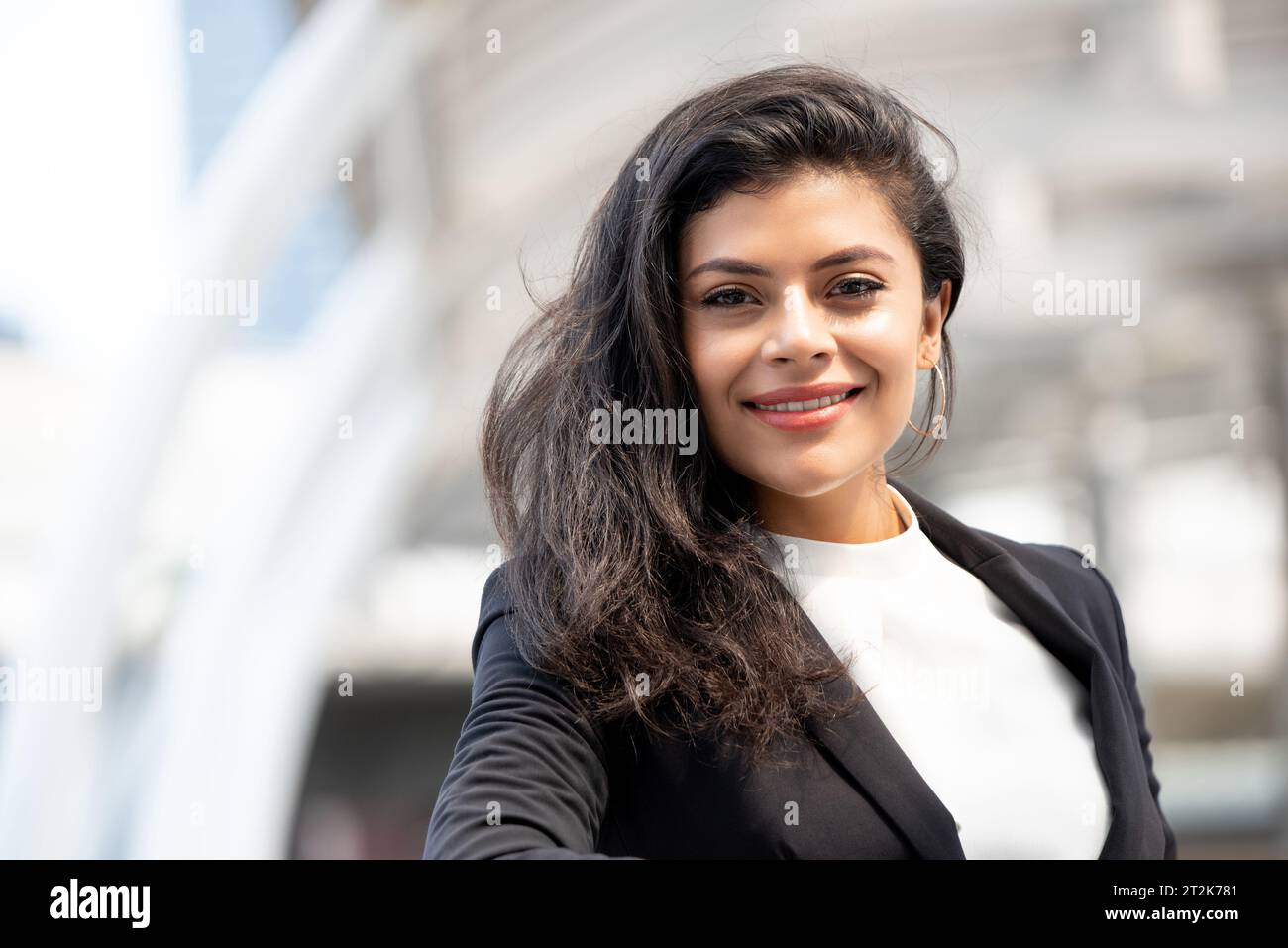 Bella donna d'affari ispanica sorridente in città Foto Stock