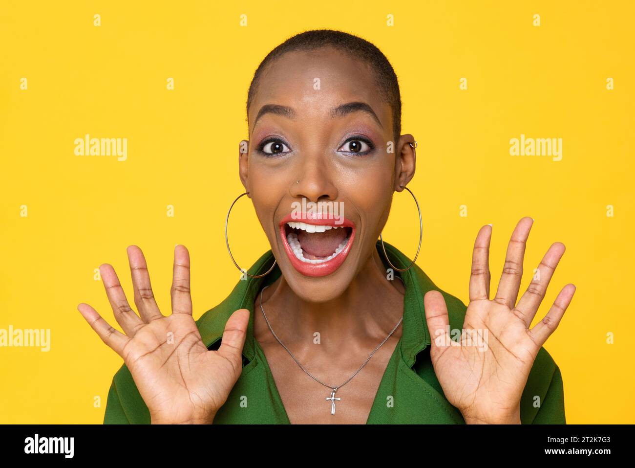 Ritratto ravvicinato di una giovane donna afro-americana spaventata con la testa rasata e le palme aperte che urlano su uno sfondo giallo isolato Foto Stock