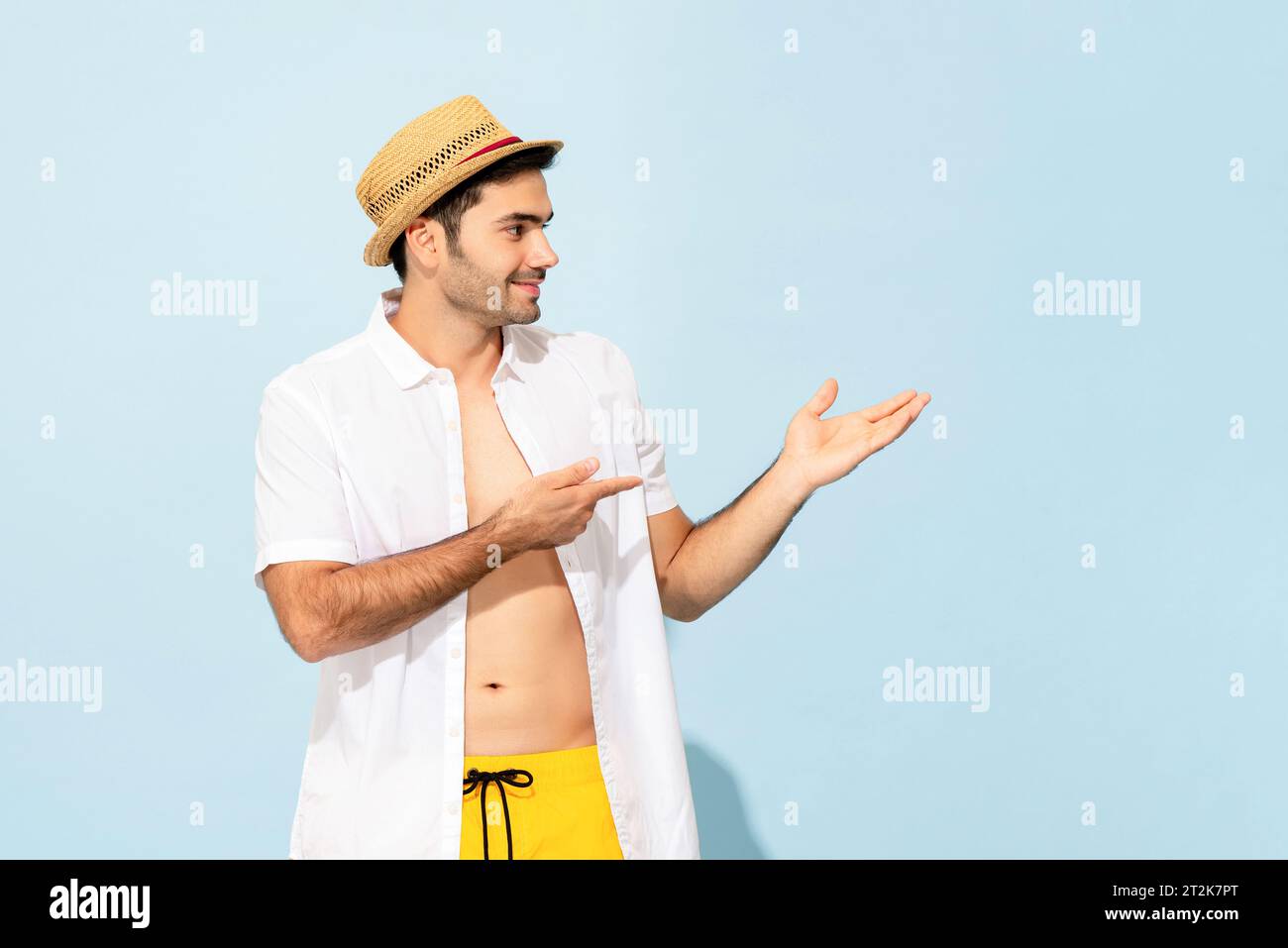 Bell'uomo caucasico in abito estivo sorridente e puntato le mani da parte in uno studio di colore blu chiaro su sfondo isolato Foto Stock