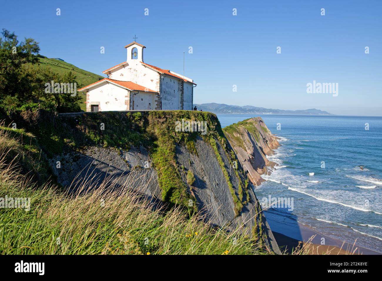 Cappella di Sant'Elme a Zumaia, situata in un'incantevole baia dove le montagne verdi scendono fino al mare, formando aspre scogliere. Foto Stock