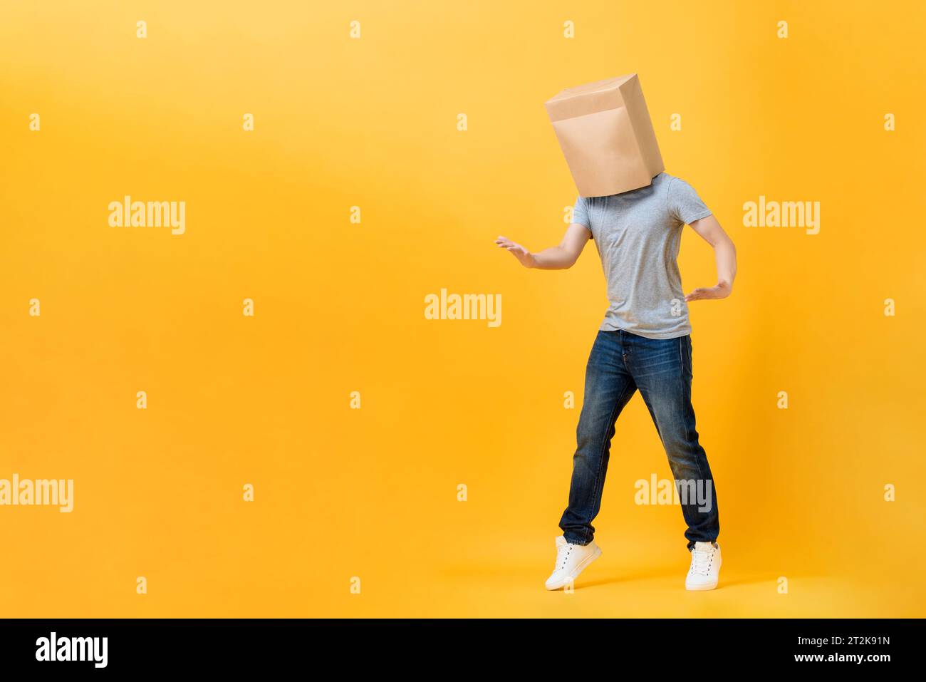 Uomo anonimo con testa coperta da buste di carta che aprono mani in studio giallo, sfondo isolato con spazio per la copia Foto Stock