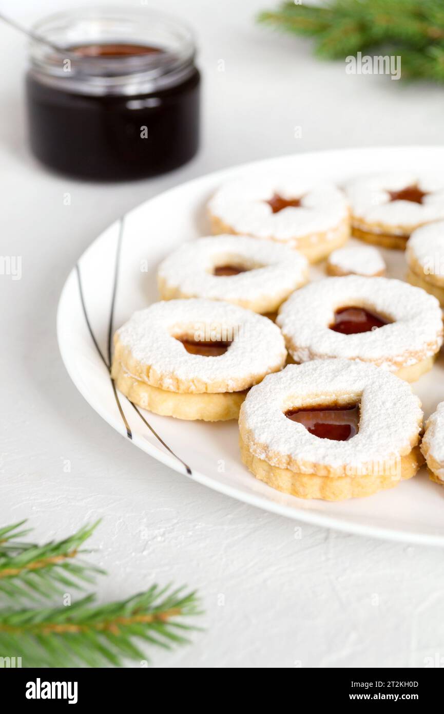 Biscotti Linzer fatti in casa con marmellata cosparsa di zucchero a velo su piatto bianco. Festività natalizie dolci natalizi, dolcetti squisiti. C Foto Stock