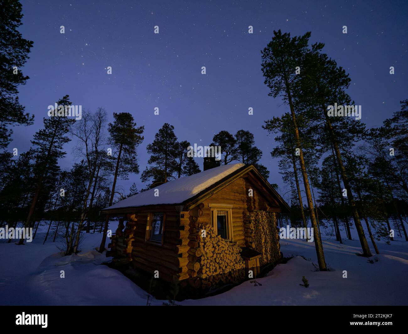 Paesaggio notturno con capanna in legno in una foresta finlandese Foto Stock