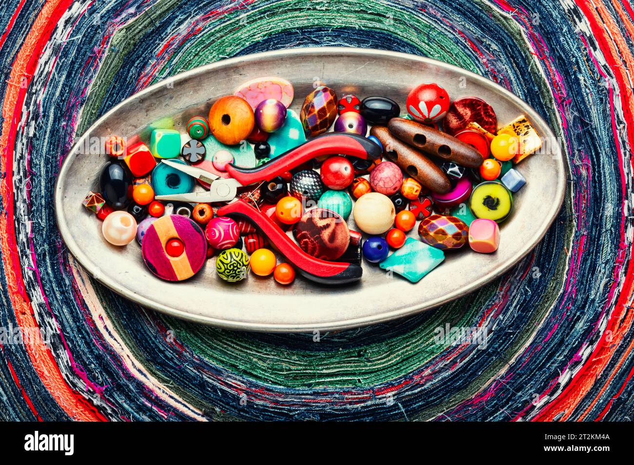 Un set di perline luminose di diversi tipi per la lavorazione dell'ago. Perline su uno sfondo variegato. Foto Stock