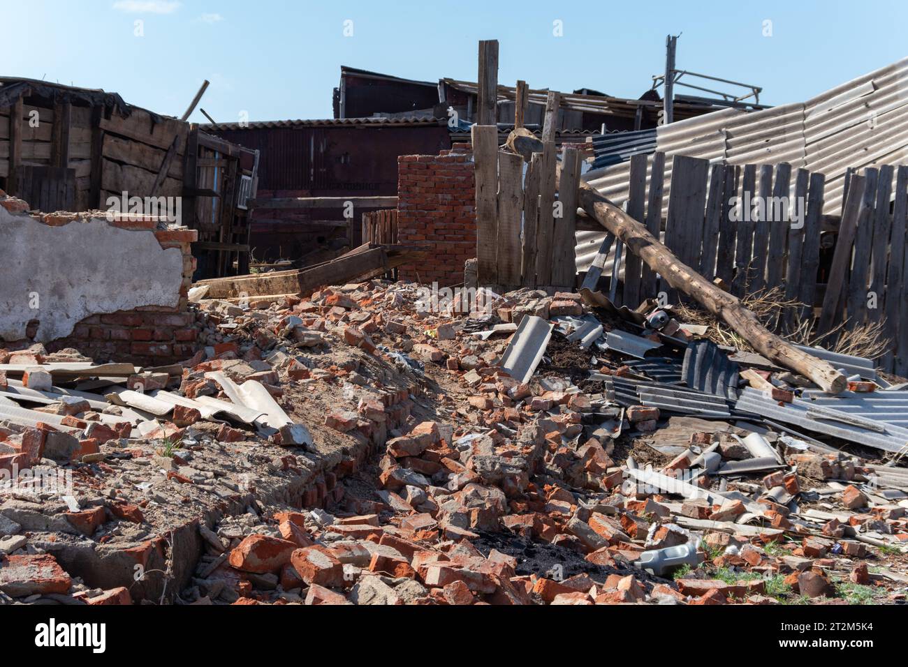 Una vecchia casa in legno in rovina. Muri rotti, tetto in rovina. Mucchi di spazzatura. Disastri naturali, guerra, terremoto. Foto Stock