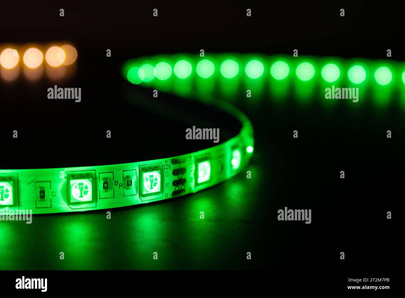 Bobina con rotolo di strisce luminose LED luminose posizionate sul tavolo, colore verde e bianco caldo Foto Stock