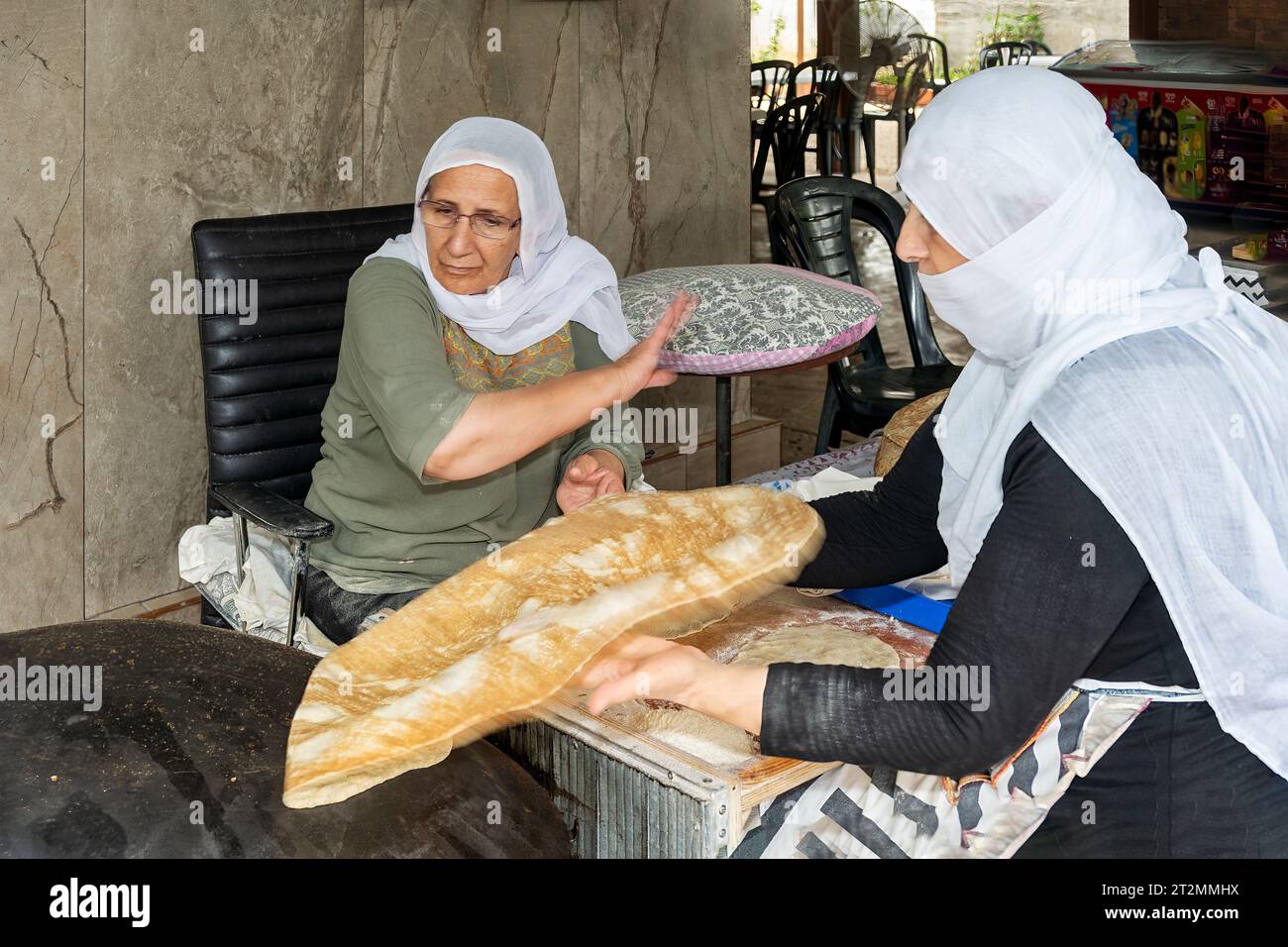 Hurfeish, Israele - 14 agosto 2023: Due donne curde preparano pita fresca in un ristorante curdo a Hurfeish, nel nord di Israele. Lanciare la pita su t Foto Stock