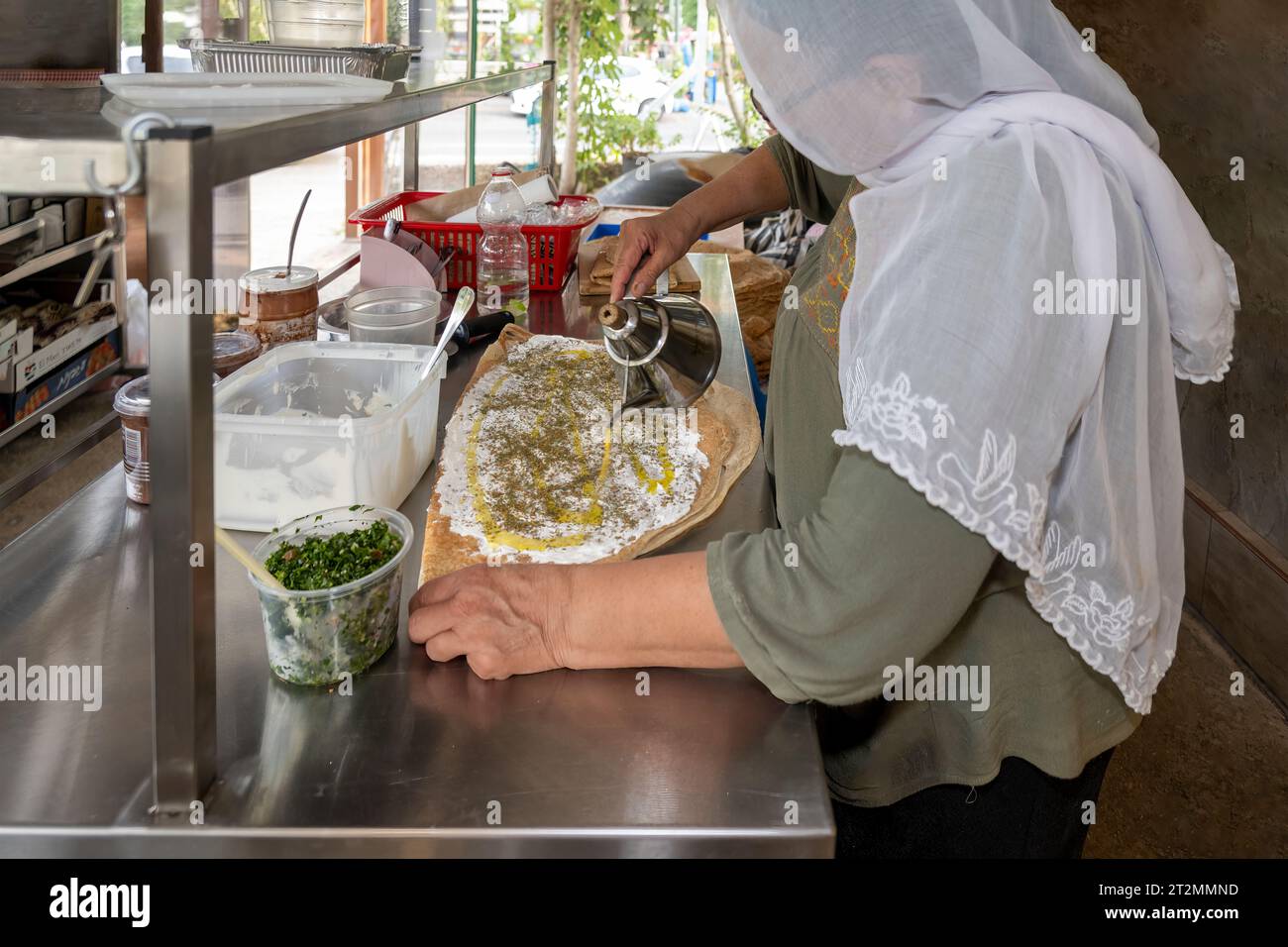 Hurfeish, Israele - 14 agosto 2023: Una donna drusa prepara la pita drusa con Labneh e Tabbouleh in un ristorante a Hurfeish, nel nord di Israele. Foto Stock