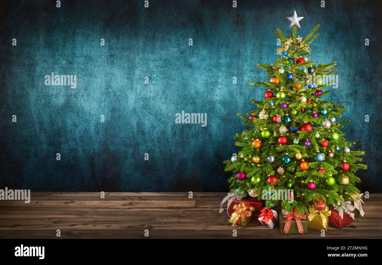 Delizioso albero di Natale decorato con ornamenti colorati collocati su pavimento di legno, con pareti in tessuto di color tè come spazio per le copie sullo sfondo Foto Stock