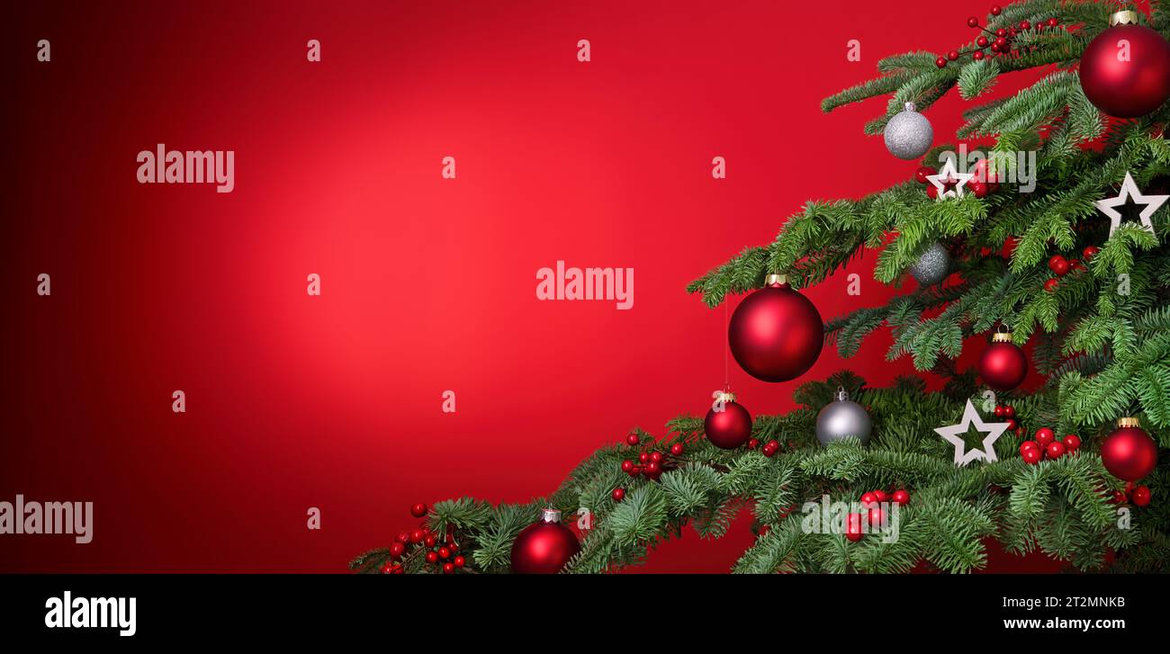 Sfondo rosso natalizio con primo piano decorato di abete e spazio copia, con bauble e stelle Foto Stock
