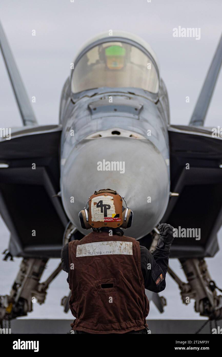 San Diego, Stati Uniti. 18 ottobre 2023. U.S. Navy Aviation Structural Mechanic di terza classe Angel Garciacastill, dirige un aereo da caccia F/A-18F Super Hornet, con il Black Aces of Strike Fighter Squadron 41 per il posizionamento sul ponte di volo della portaerei classe Nimitz USS Abraham Lincoln operante sull'Oceano Pacifico, 18 ottobre, 2023 al largo della costa di San Diego, California. Crediti: MC2 Clayton Wren/U.S. Navy/Alamy Live News Foto Stock