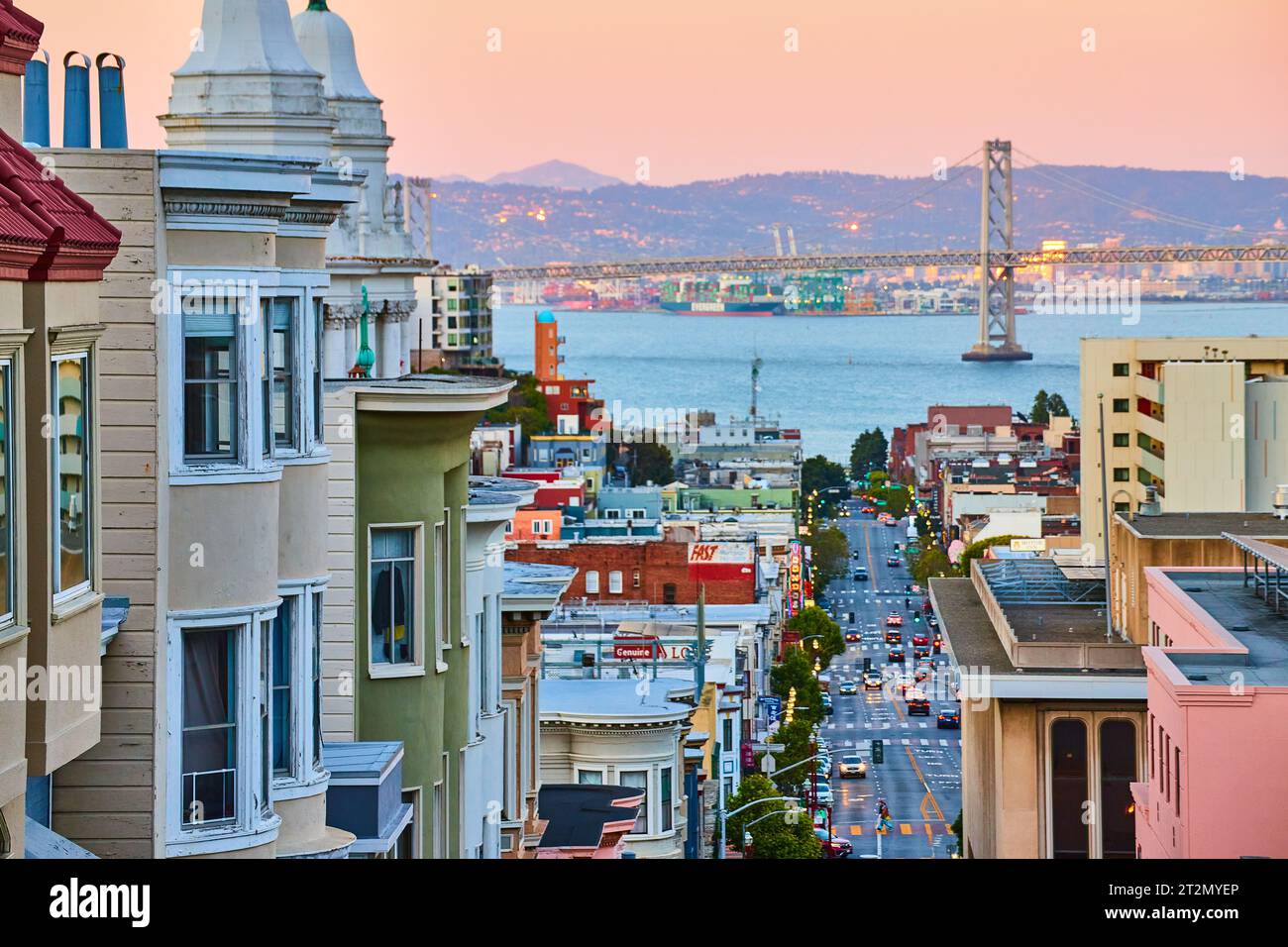 Illuminazione rosa del sorgere del sole sull'area residenziale di San Francisco con il ponte Oakland Bay Bridge e la vista della baia Foto Stock