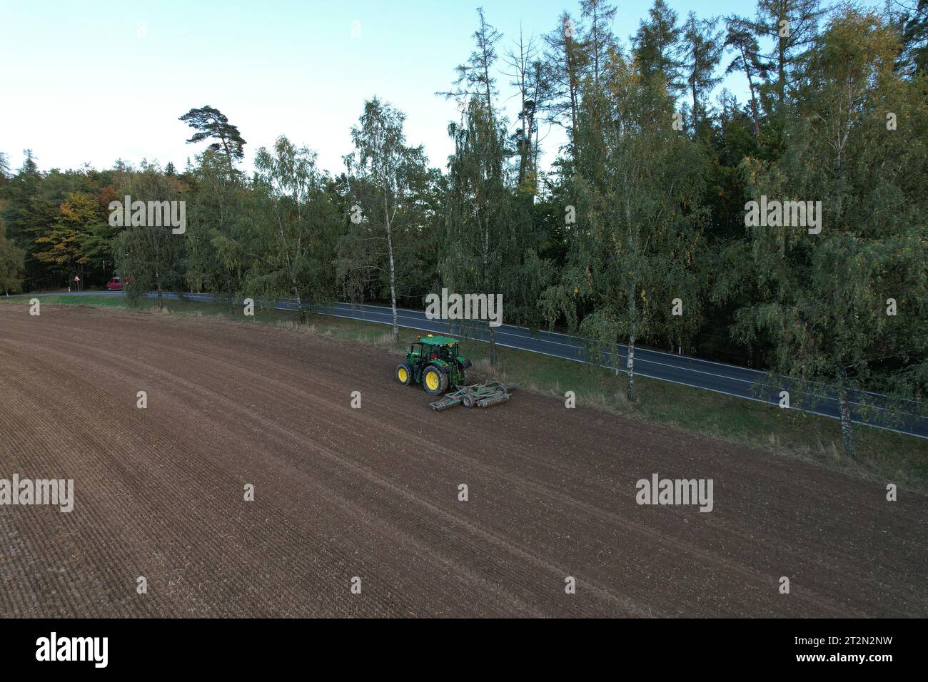 Agricoltore con trattore semina-semina colture in campo agricolo. Piante, frumento.allentamento del suolo in un campo con colture agricole, colpo aereo. La trac Foto Stock