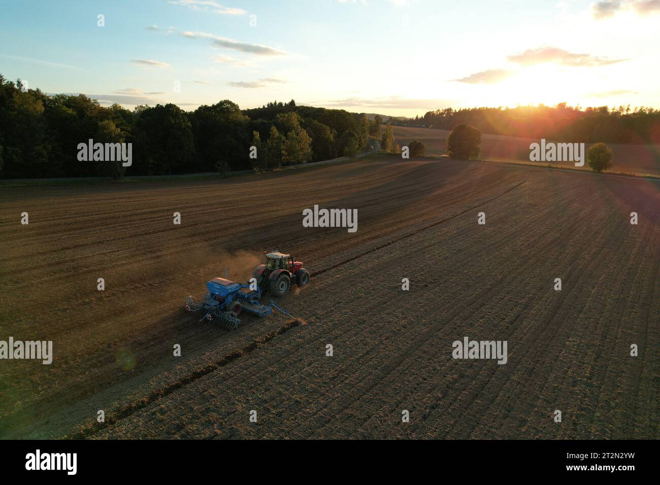 Agricoltore con trattore semina-semina colture in campo agricolo. Piante, frumento.allentamento del suolo in un campo con colture agricole, colpo aereo. La trac Foto Stock