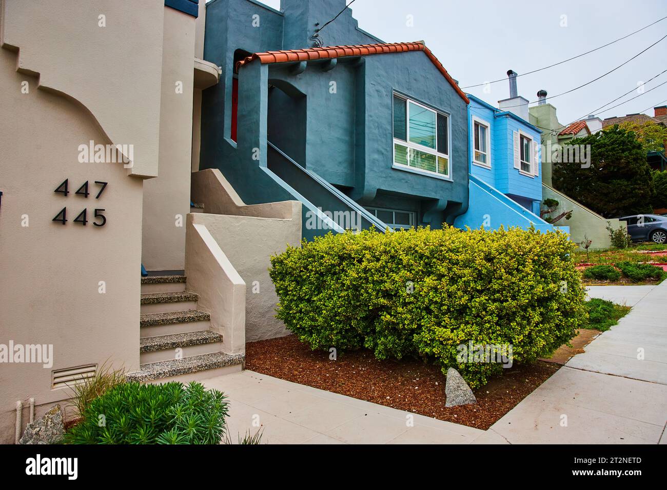 Marciapiede accanto a diverse case che conducono oltre la siepe verde fino ai gradini che salgono sulla casa bianca  Foto Stock