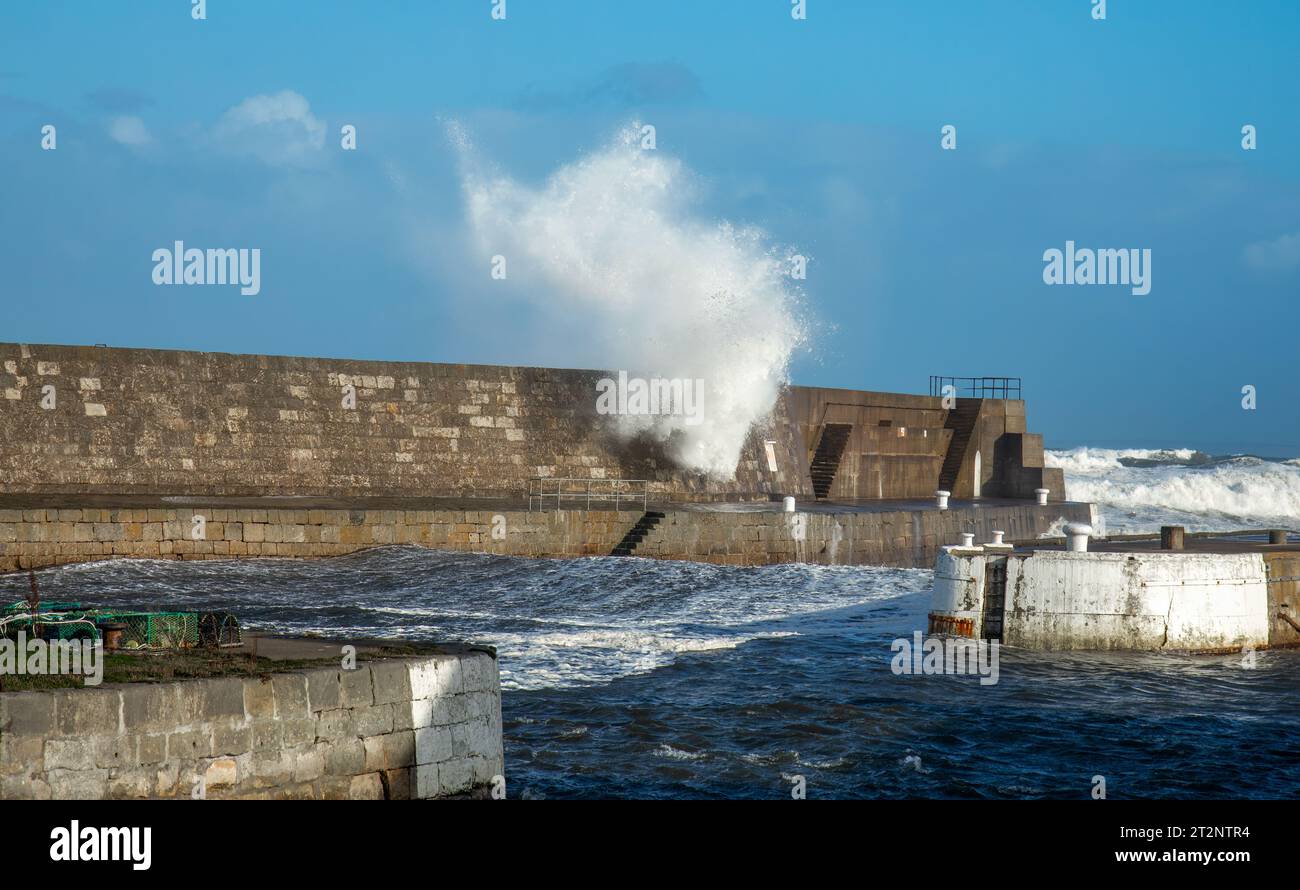 Onde che si infrangono su un muro del porto durante la tempesta Babet Foto Stock