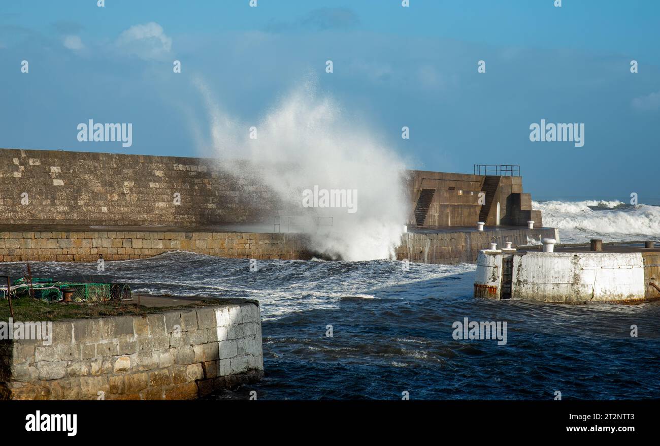 Onde che si infrangono su un muro del porto durante la tempesta Babet Foto Stock
