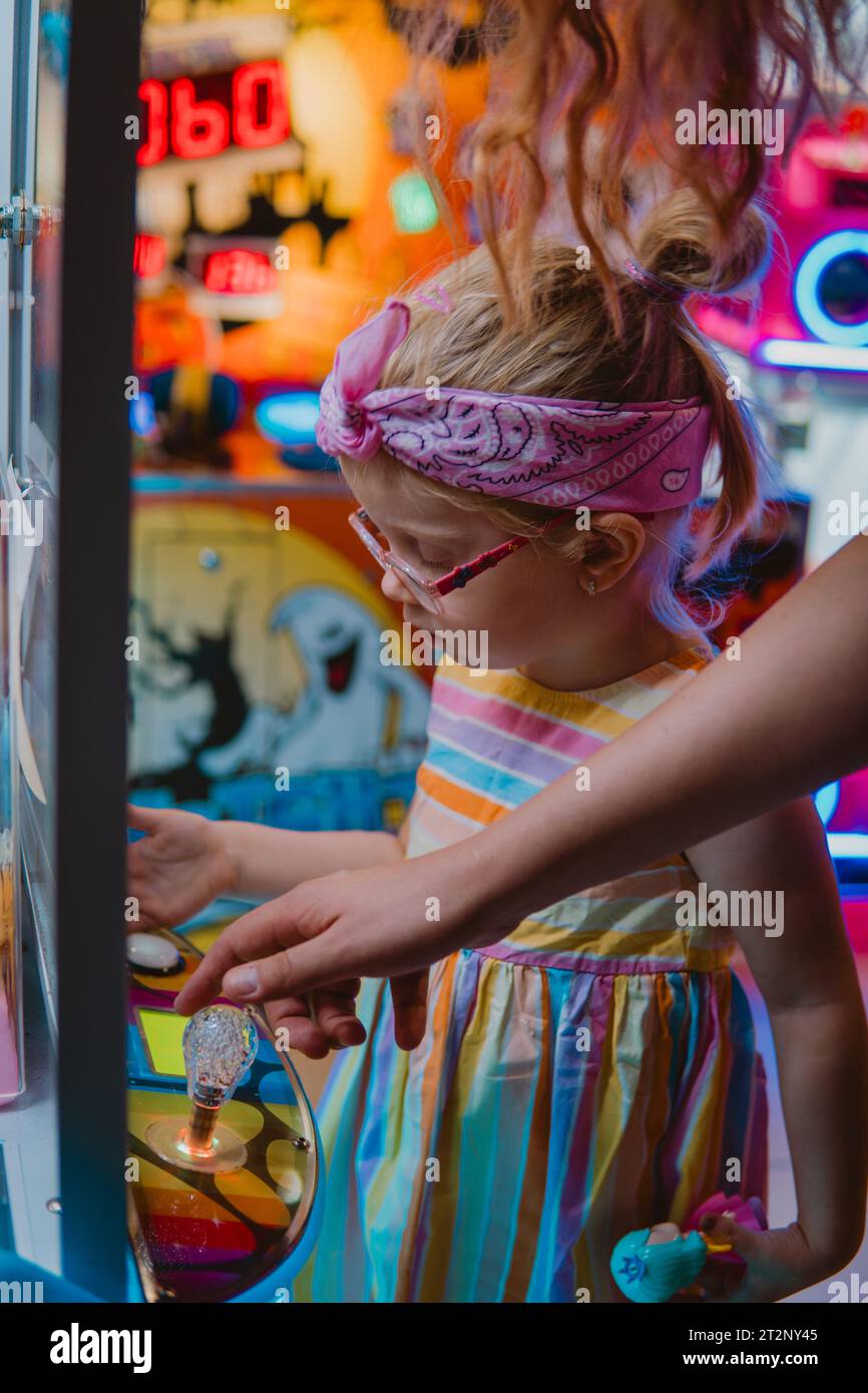 Una bambina che gioca su una macchina per artigli Foto Stock