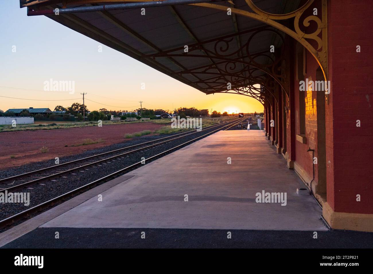 Il sole sorge alla fine di una lunga banchina vuota della stazione ferroviaria di Cobar nel nuovo Galles del Sud, Australia Foto Stock