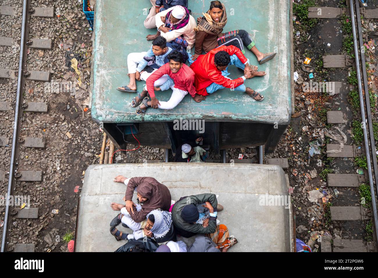 I passeggeri a basso reddito rischiano la vita viaggiando sul tetto e tra le carrozze di un treno in movimento a Dacca, Bangladesh. Foto Stock