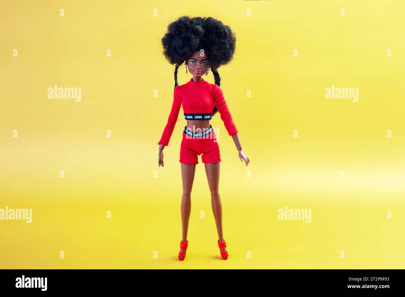 9 ottobre 2023. Barnaul, Russia: Bambola Barbie afroamericana con capelli neri in un vestito rosso su sfondo giallo. Foto Stock