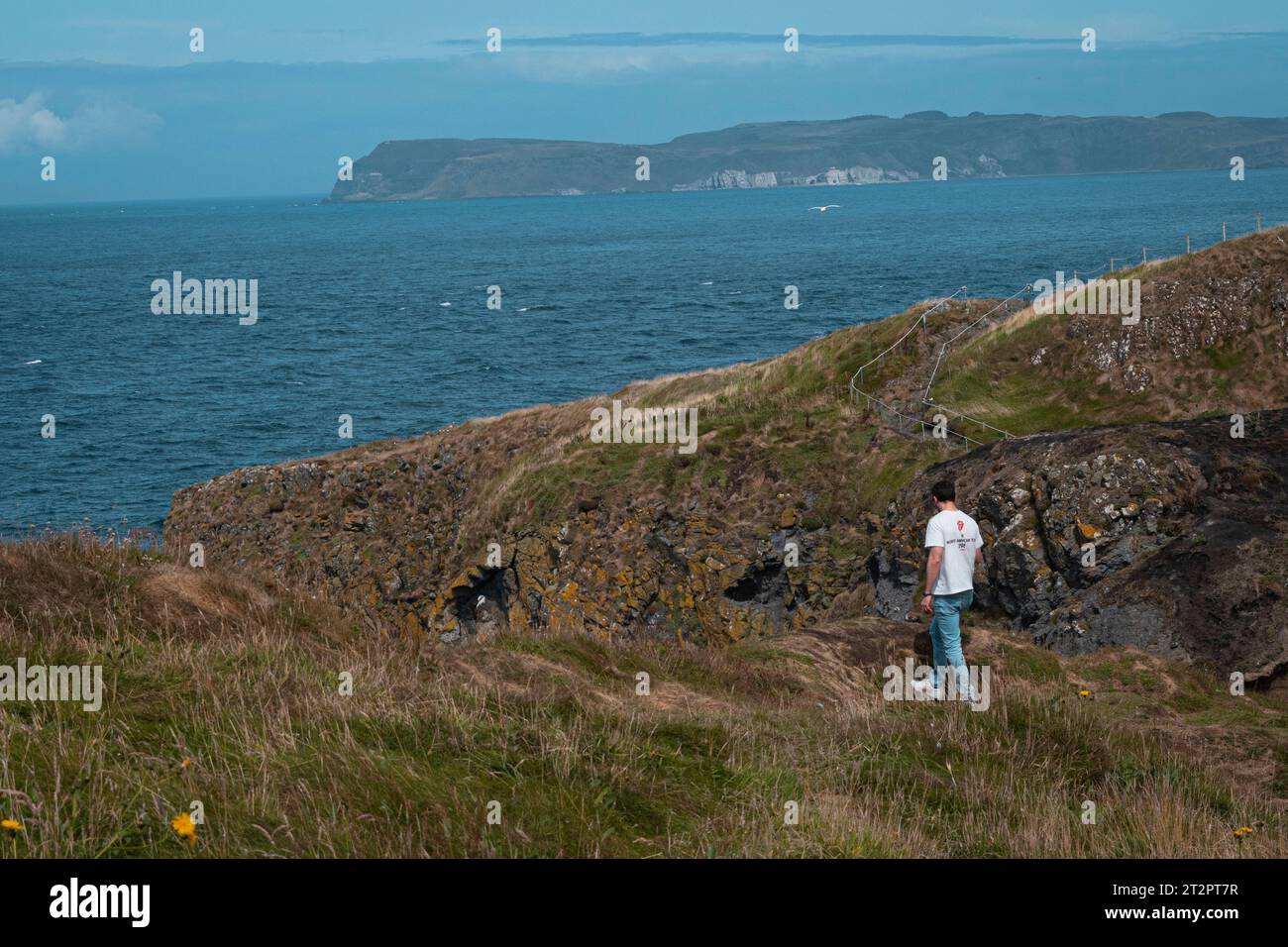 Un tizio in piedi sulla costa dell'Irlanda del Nord Foto Stock