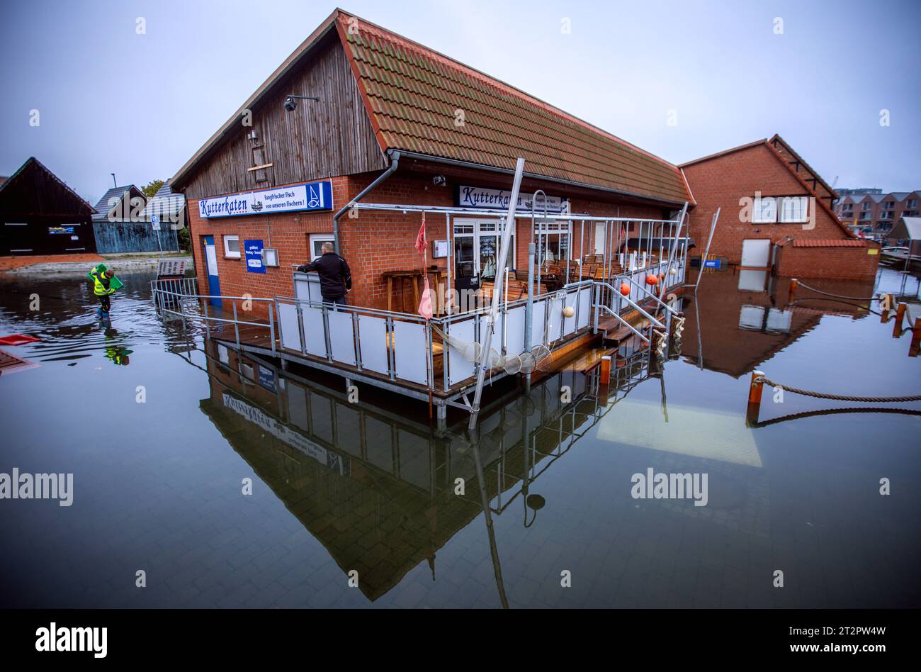 Wismar, Germania. 21 ottobre 2023. Gli edifici del porto di pesca sono in acqua dopo l'ondata di tempesta sulla costa del Mar Baltico. Il lavoro di pulizia inizia domattina. A Wismar, il livello dell'acqua è rimasto sotto i 1,60 metri nella notte del 21.10.2023 e scese a meno di 1,50 metri la mattina presto. Credito: Jens Büttner/dpa/Alamy Live News Foto Stock