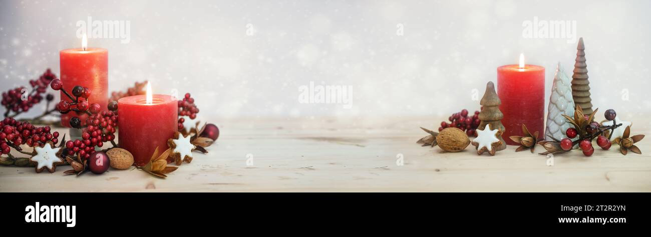Decorazione invernale in formato panoramico con candele rosse, piccoli alberi artificiali e frutti di bosco per Natale, Avvento e Capodanno contro un bo leggero e nevoso Foto Stock