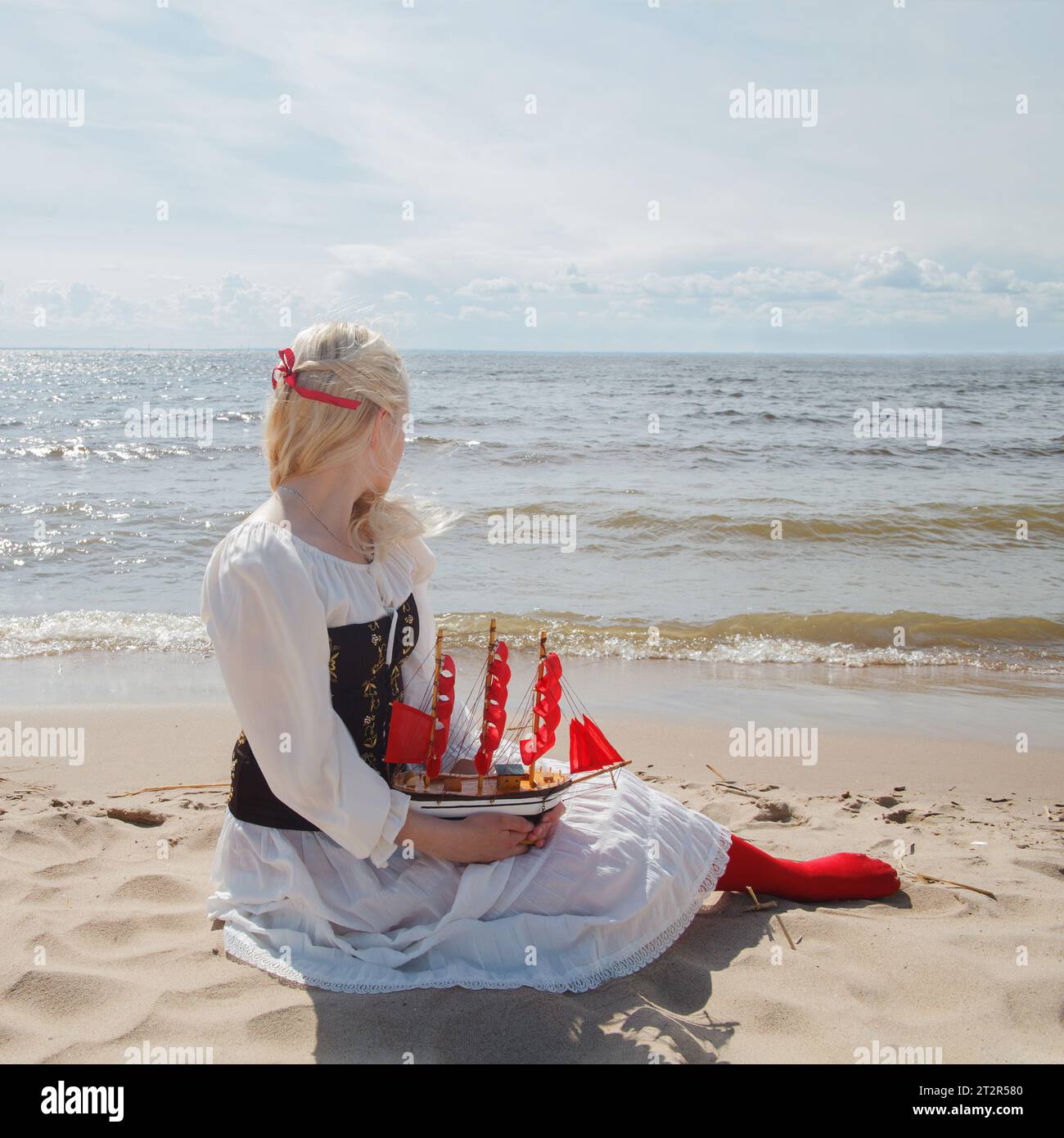 Giovane bella donna che aspetta il marinaio sulla riva del mare guardando l'orizzonte Foto Stock