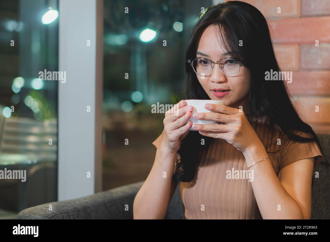 una ragazza beve un caffè in una caffetteria, bellissimi capelli di una ragazza Foto Stock